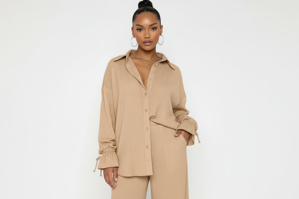 Woman wearing a beige button-up shirt with a plain background